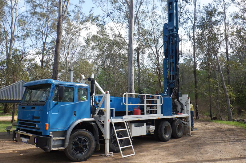 Blue Drilling Truck with Equipment Set up In a Forested Area — Bore Drilling in Bundaberg, QLD
